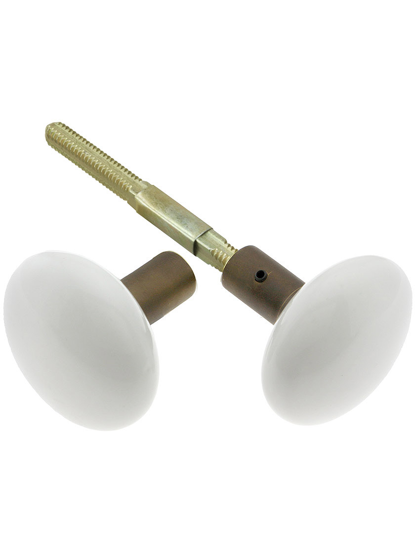 Pair of White Porcelain Doorknobs with Brass Shank in Antique Brass.